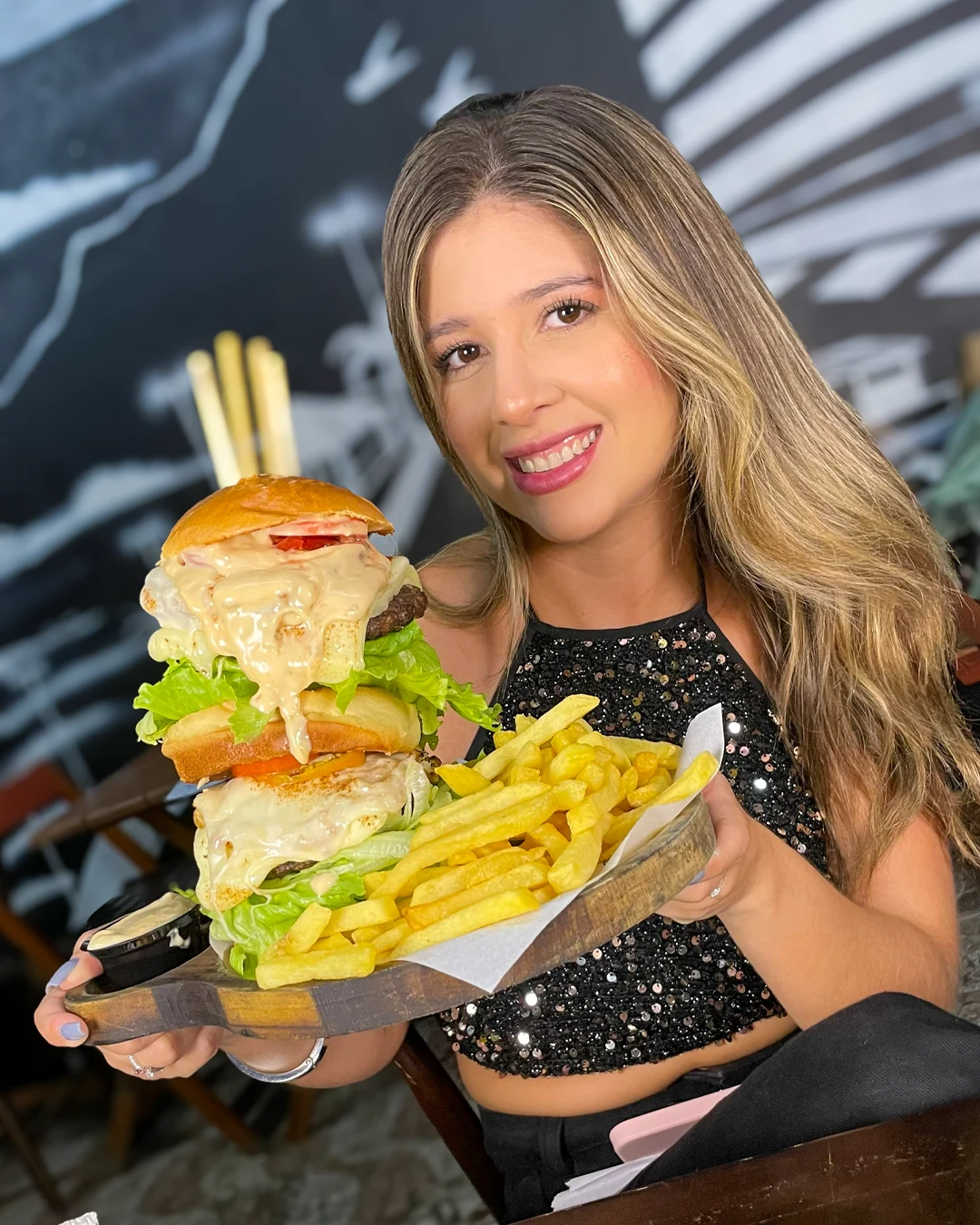 Cliente segurando um lanche artesanal acompanhado de batatas fritas